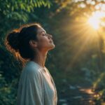 Person facing warm golden morning sunlight outdoors, peaceful and grounded